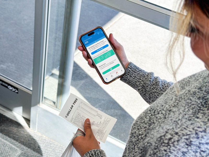a person holding an iphone with a coupon app in the dollar tree store
