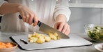 a person chopping potatoes on a titanium cutting board