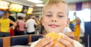 child eating a burger in a fast food restaurant