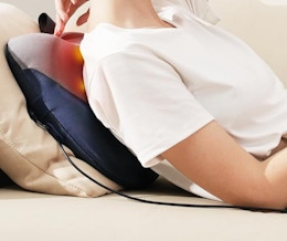 a person laying on a couch with a back massager