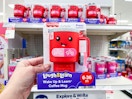 hand holding a fisher price coffee mug in front of a target shelf