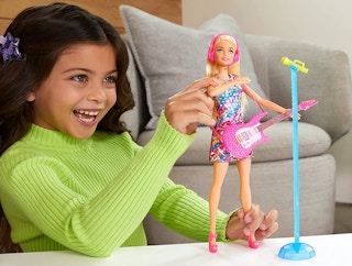 A girl playing with a Barbie and musical accessories