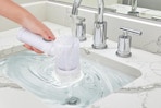 a hand holding a spin scrubber in a sink