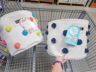 two sets of canvas storage bins with pom poms in a cart