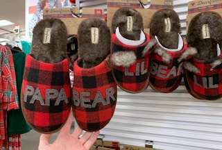 A hand holding Dearfoams Papa Bear slippers in plaid.