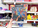hand holding a fao schwarz magnetic tile set in front of target shelves