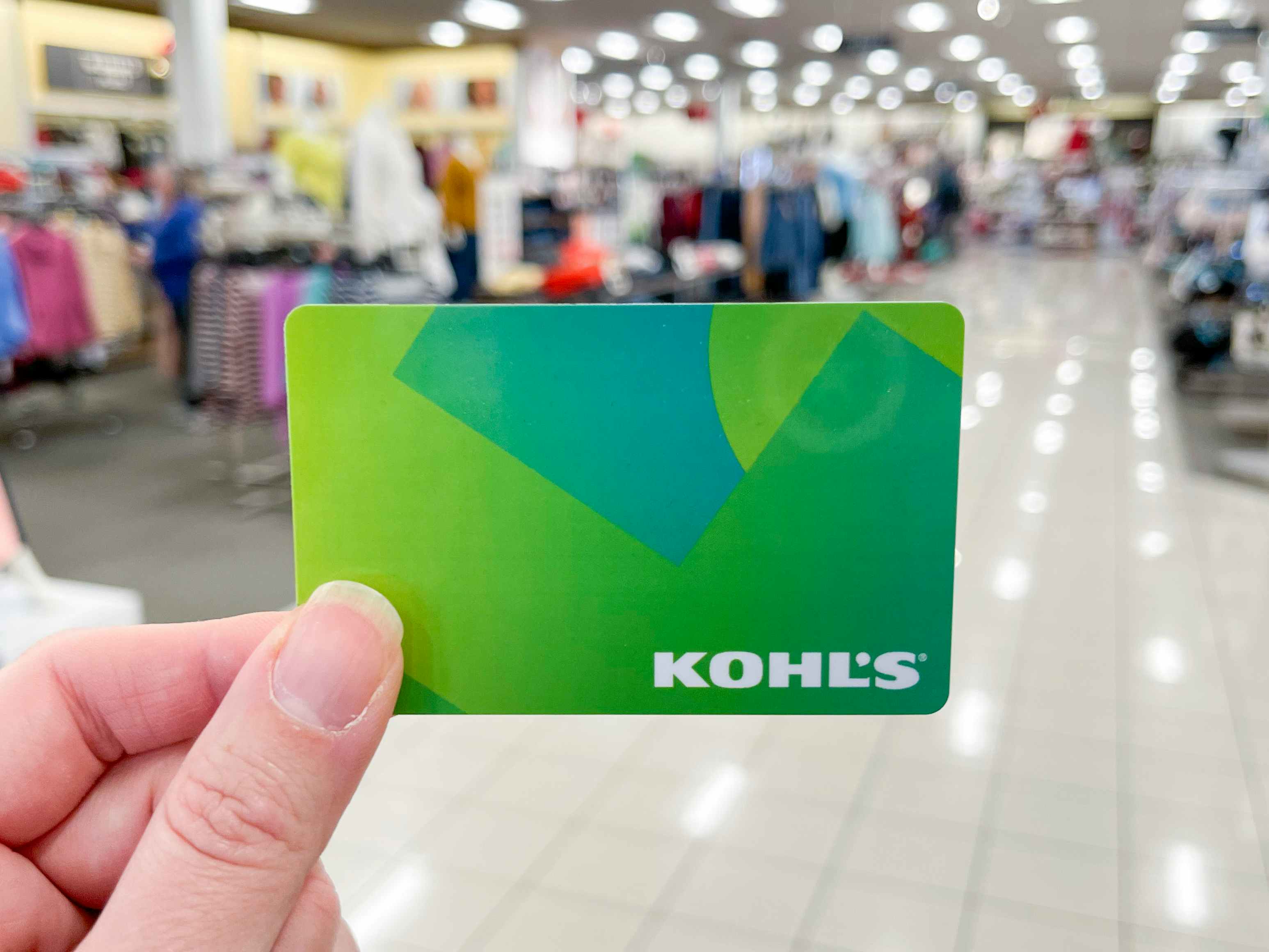 A person holding up a Kohl's gift card