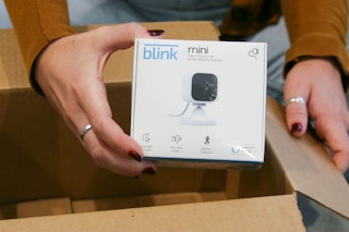 A person taking a Blink Mini camera out of a delivery box.