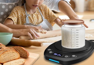 a sourdough jar on a warmer next to a little kid rolling dough