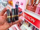 hand holding revlon lipstick in front of target shelf