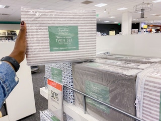 someone holding up a sheet set bag in store