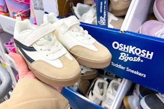 hand holding a pair of oshkosh shoes