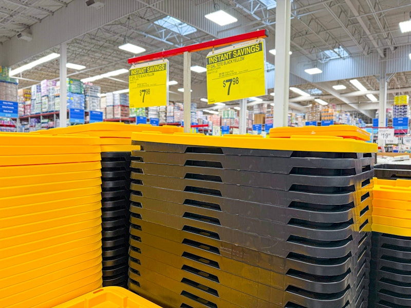 sale sign for $7.98 over stacks of black storage totes with yellow lids