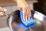 a woman using a sponge on a pan