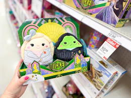 hand holding a squishmallows wicked plush set in front of a target shelf