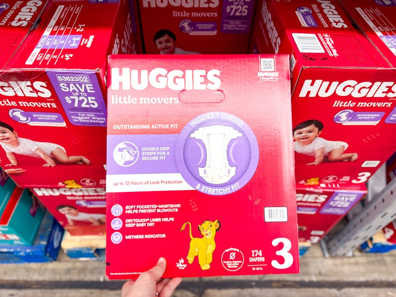 person grabbing a box of huggies diapers