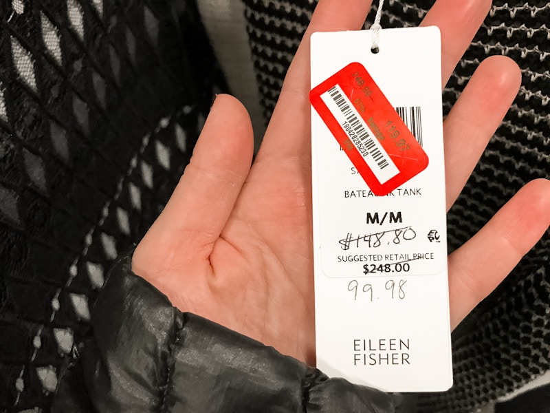 A person holding a price tag with a lower price hand written on it then what is visible on the red price tag. 