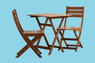 two patio chairs and a table on a solid color background