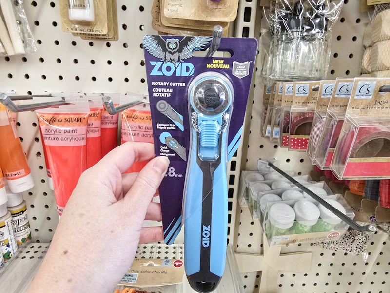 person grabbing a zoid rotary cutter off a hook