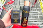 person holding a sheamoisture bar soap next to a body wash in a cart