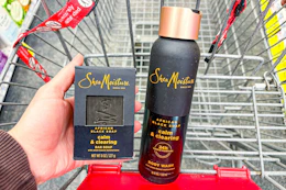 person holding a sheamoisture bar soap next to a body wash in a cart