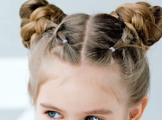 A little girl with a bun hairstyle with rubber bands