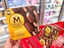 hand holding one box of Magnum mini ice cream bars in front of shopping cart with two more boxes inside