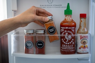 A person pulling Cayenne pepper from a shelf in a refrigerator