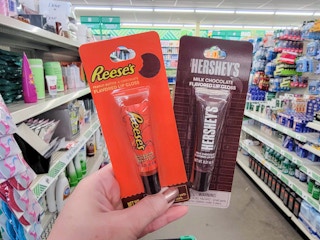 hand holding a reese's and a hershey's flavored lip gloss