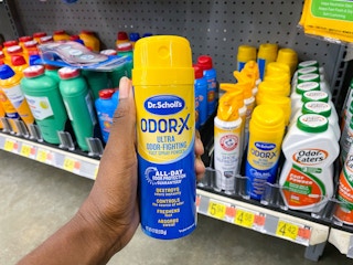 Hand holding a can of Dr. Scholl's Odor-X Spray Powder at Walmart