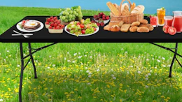 a table outside with a black tablecloth and food on it