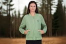 Woman modeling a green Reebok windbreaker jacket in outdoor environment 