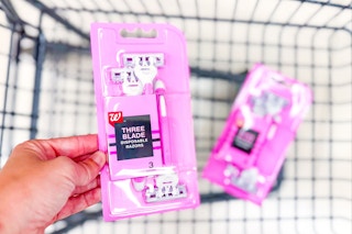person putting a pack of disposable razors in a cart with another pack in it