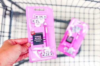 person putting a pack of disposable razors in a cart with another pack in it