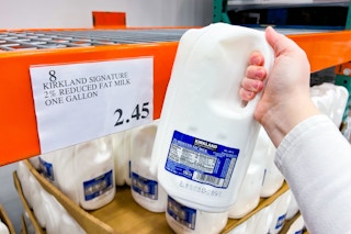 hand holding a gallon of kirkland milk at costco
