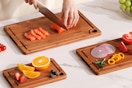 cutting boards B0FHW3MNKN Three bamboo cutting boards on a marble countertop with veggies and fruits on them