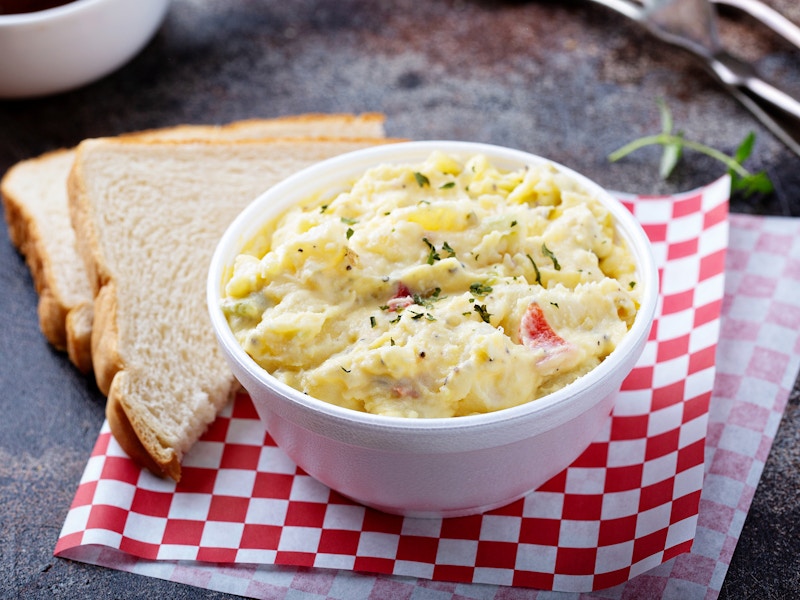 A bowl of potato salad next to some slices of bread