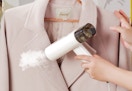 a person using a clothing steamer on a pink blazer
