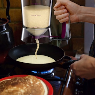 A hand squeezing batter out of a batter dispenser.