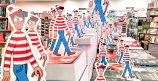 A bunch of Waldo standees on a table of books in a bookstore