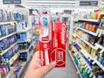 hand holding colgate toothpaste and toothbrush in walgreens
