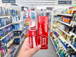 hand holding colgate toothpaste and toothbrush in walgreens