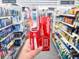 hand holding colgate toothpaste and toothbrush in walgreens