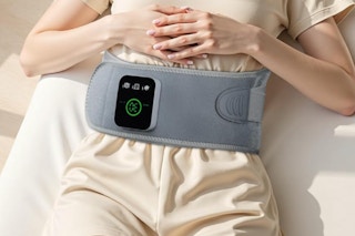 Woman using the purella Cordless Heating Massage Pad on her lower back lying down.