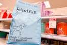 hand holding a kindful dog food bag in front of a target shelf