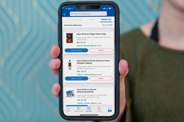 Hand holding a phone showing coupons page on the kroger app