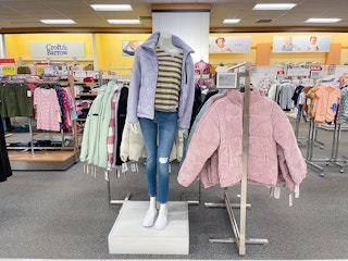 An area shot of jackets and coats with a mannequin standing in the middle wearing a purple coat.
