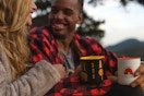 man and woman holding REI mugs and smiling at each other outside