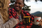 man and woman holding REI mugs and smiling at each other outside