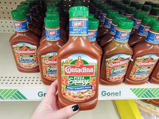 hand holding a bottle of pizza sauce